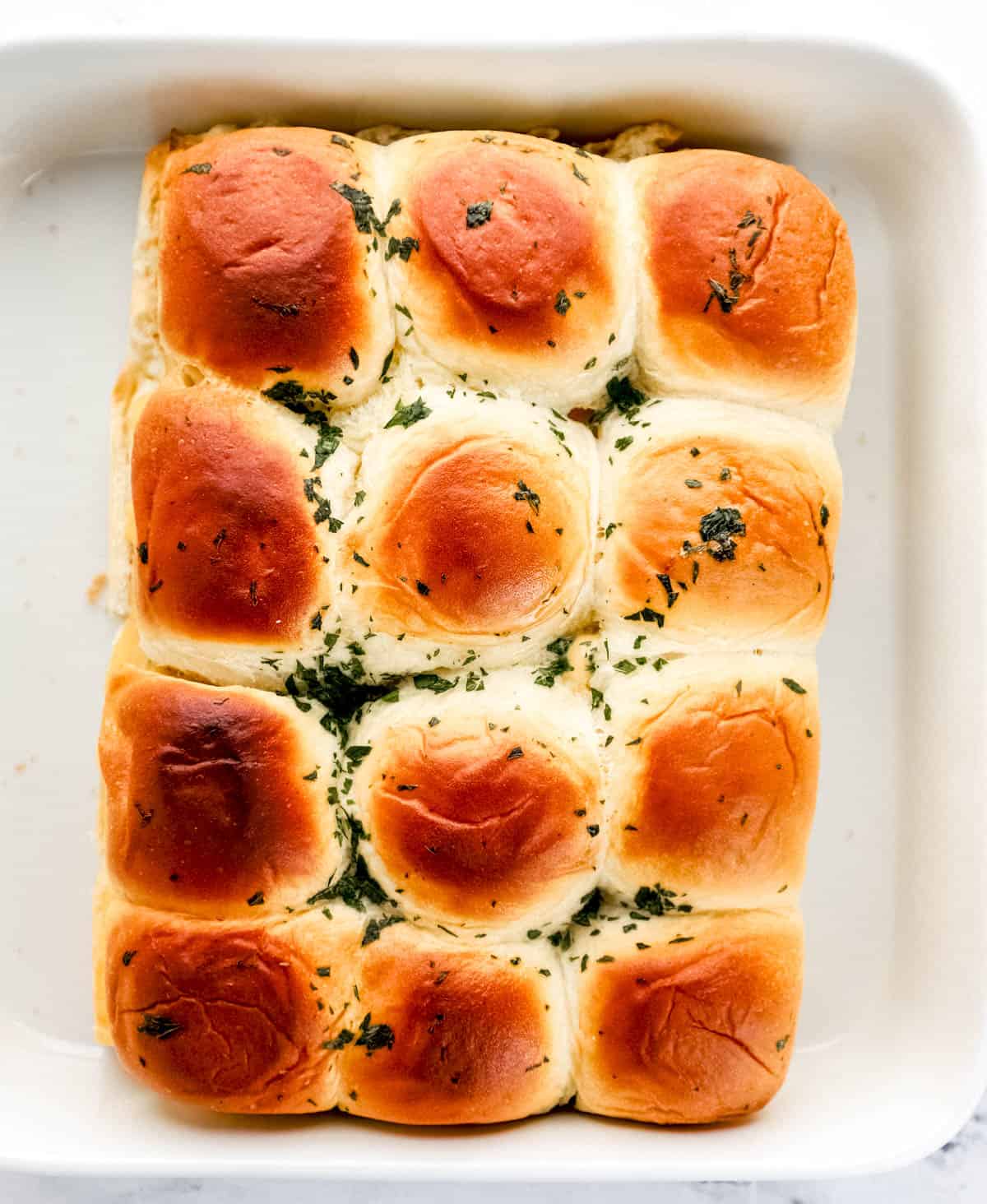 Baked sliders in white baking dish. 
