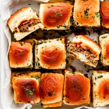 Overhead view of cheeseburger sliders in parchment lined baking dish.