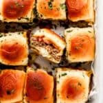 Close up overhead view of baked sliders in parchment lined baking dish.