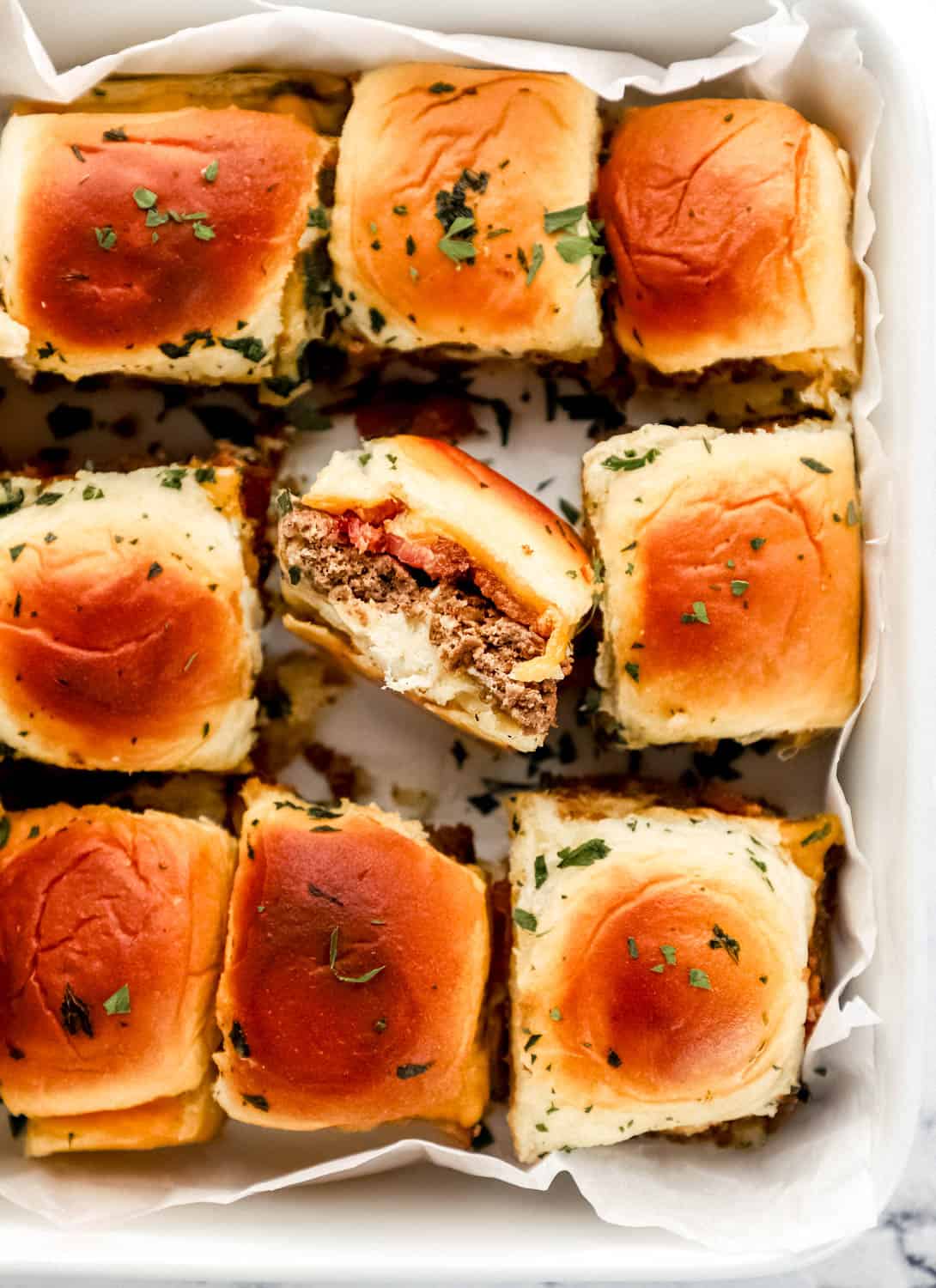 Close up view of finished sliders in parchment lined baking dish. 