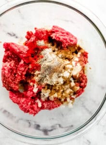 Hamburger ingredients added to glass mixing bowl.