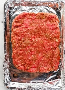 Beef mixture pressed into foil lined sheet pan.