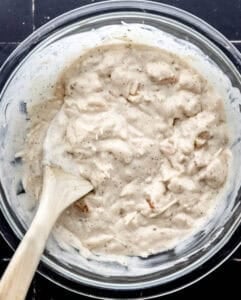 Alfredo sauce ingredients in glass mixing bowl with wooden spoon.