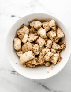 Overhead view of cooked chicken in white bowl.
