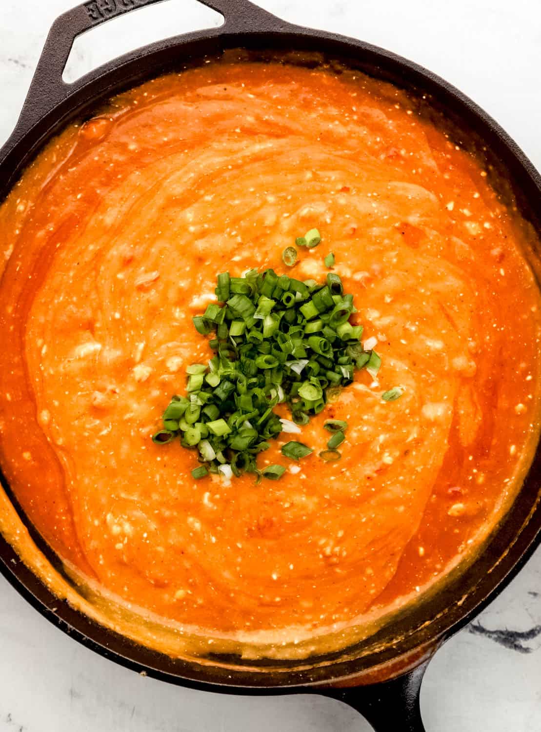 Cheesy Chicken Enchilada Pasta Simply LaKita 14 Overhead view of pasta sauce in cast iron skillet topped with green onions.