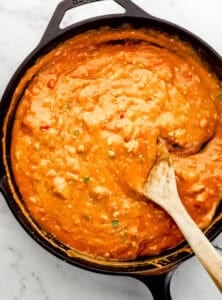 Sauce ingredients combined in cast iron skillet with wooden spoon.