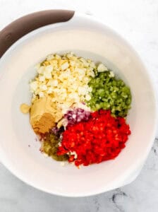 Salad ingredients added in large white mixing bowl.