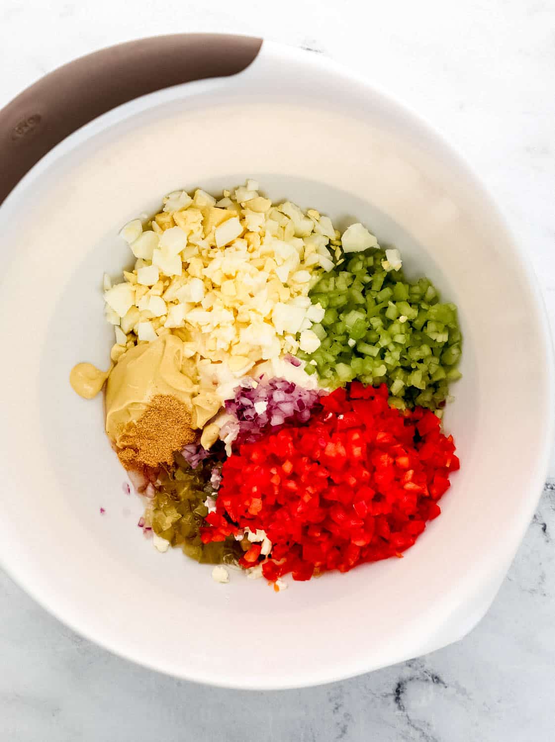 Dressing ingredients and diced veggies added to large white mixing bowl. 