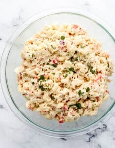 Overhead view of finished pasta salad in glass bowl topped with parsley.