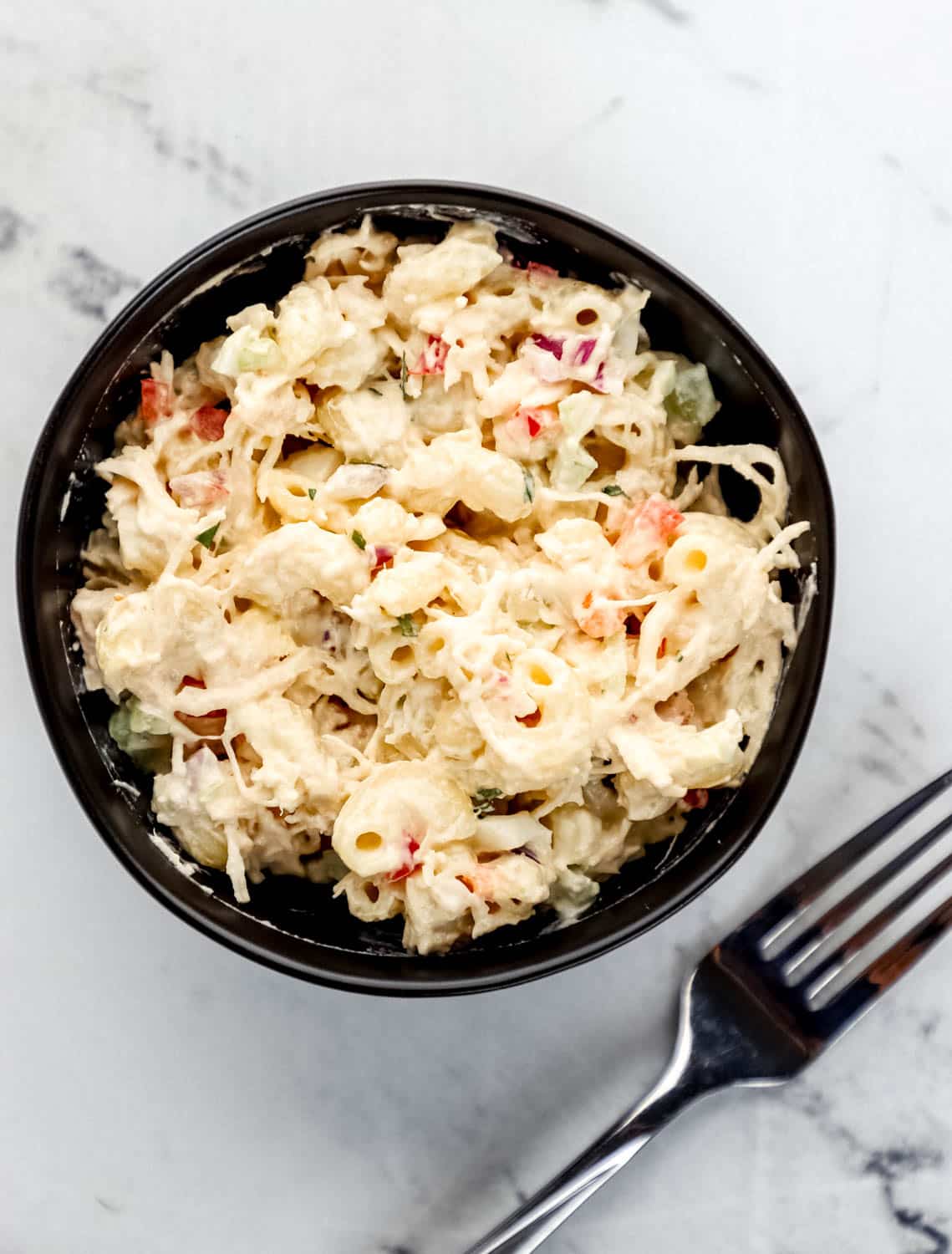Overhead view of small black bowl with finished pasta in it by a fork. 
