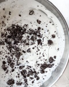 Overhead view of stand mixer bowl with cookie and cream ice cream in it.