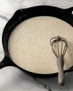 Milk added to cast iron skillet with other gravy ingredients.