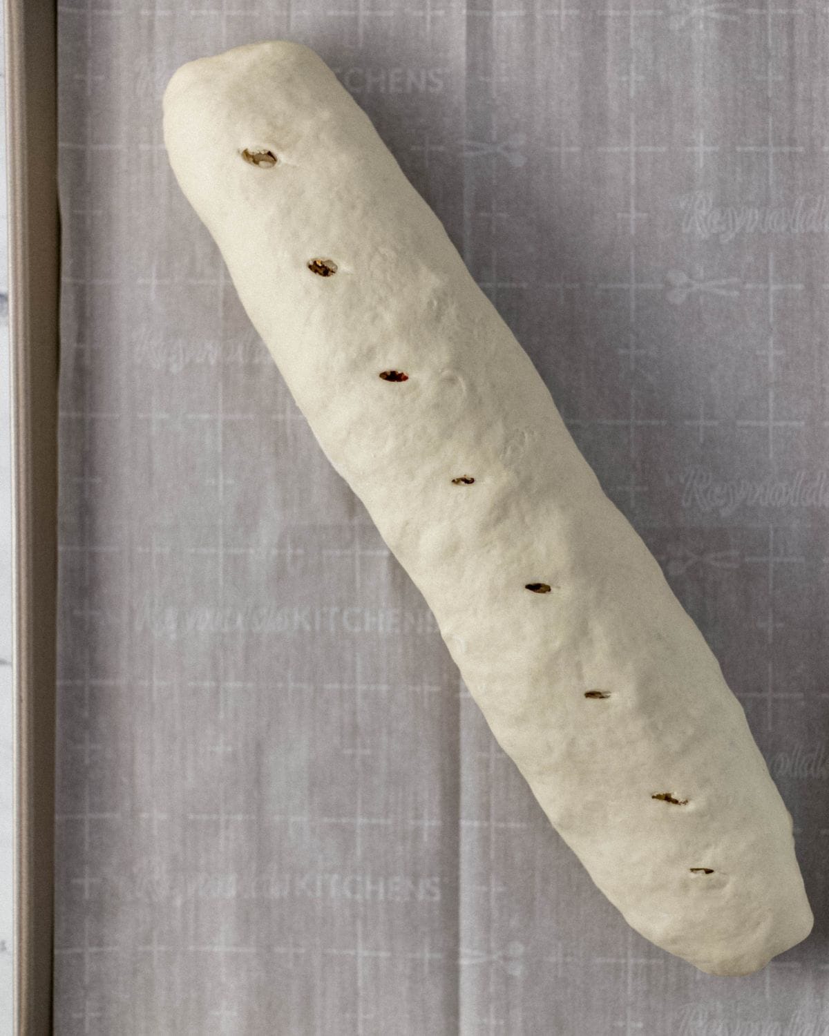 Rolled bread on parchment lined baking sheet before baking. 