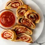 Close up overhead view of sliced bread on white plate with small bowl of sauce.