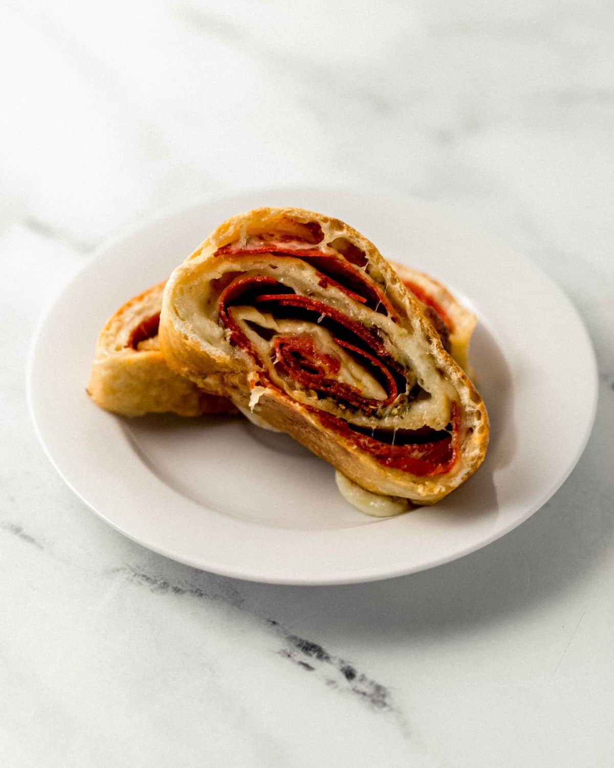 Small white plate with two slices of pepperoni bread on it. 
