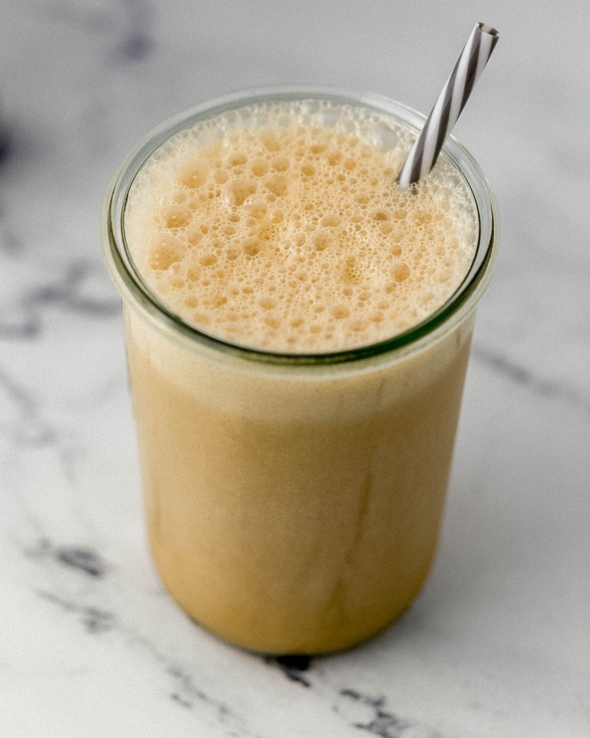 Close up view of finished frappe in glass with straw in it. 