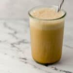 Close up side view of coffee in a glass on marble surface.