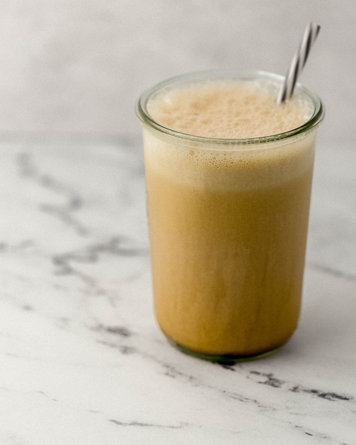 Close up side view of coffee drink in tall glass with straw in it. 