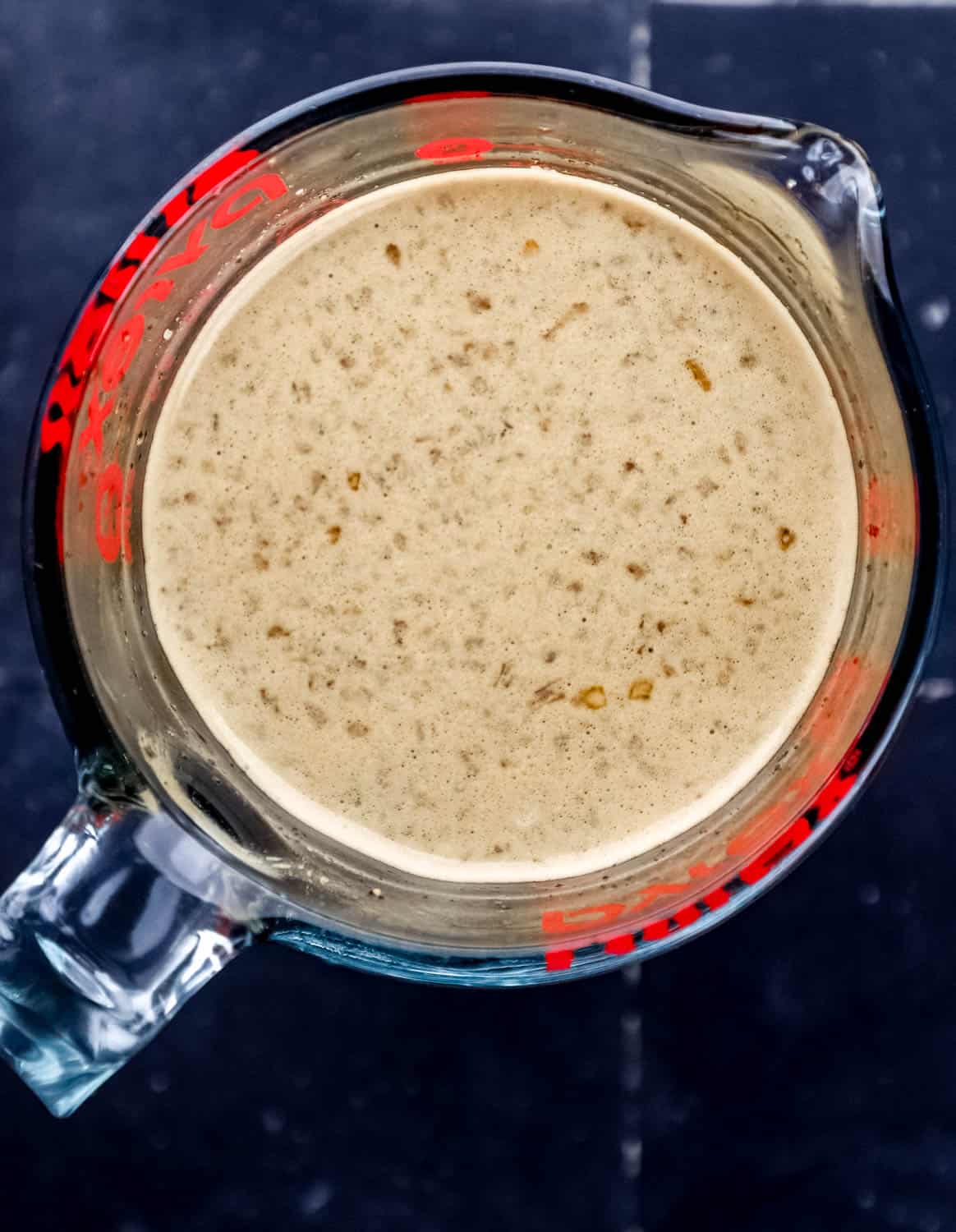 Overhead view of sauce ingredients blended in glass measuring cup. 