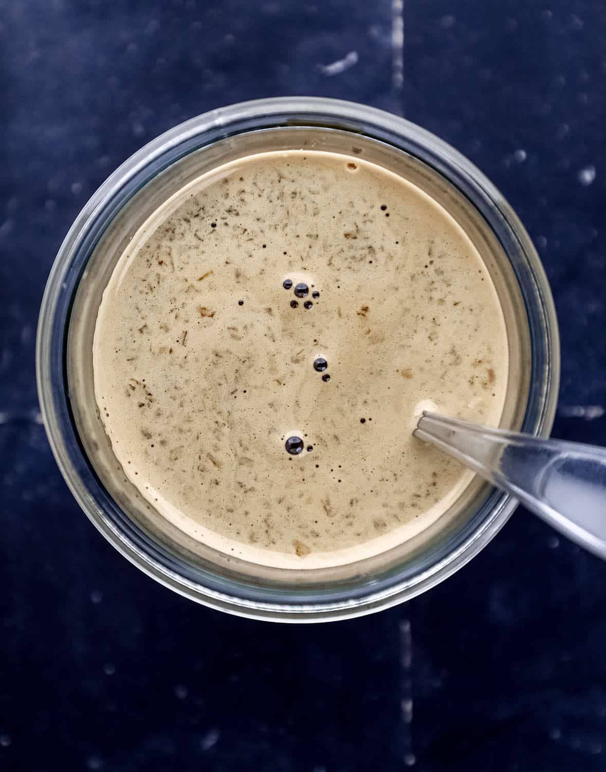 Overhead view of finished sauce in glass jar with spoon in it. 