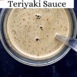 Close up overhead view of finished sauce in glass jar with spoon on pin with text overlay.