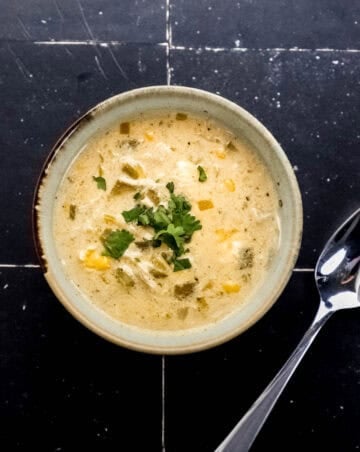 Overhead view of bowl of chili topped with herbs by spoon.