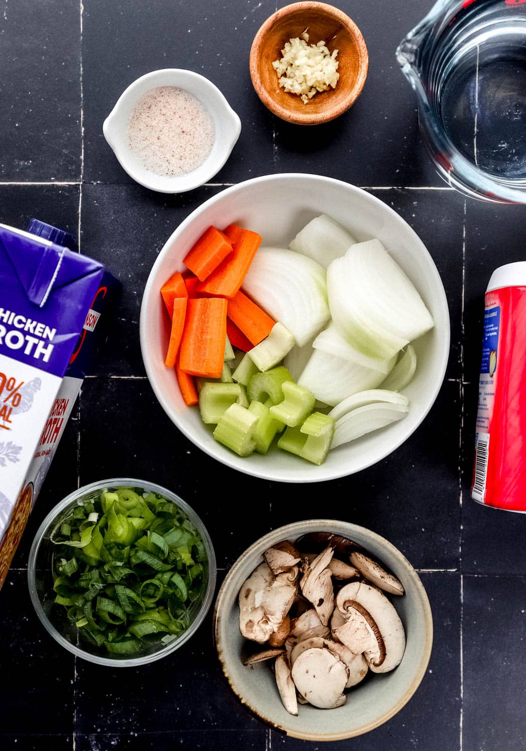 Overhead view of ingredients needed to make soup in separate bowls. 