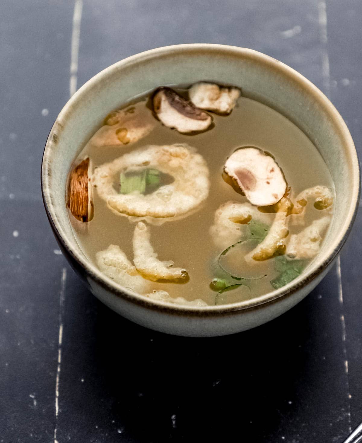 Close up front view of bowl of soup on black tile surface. 