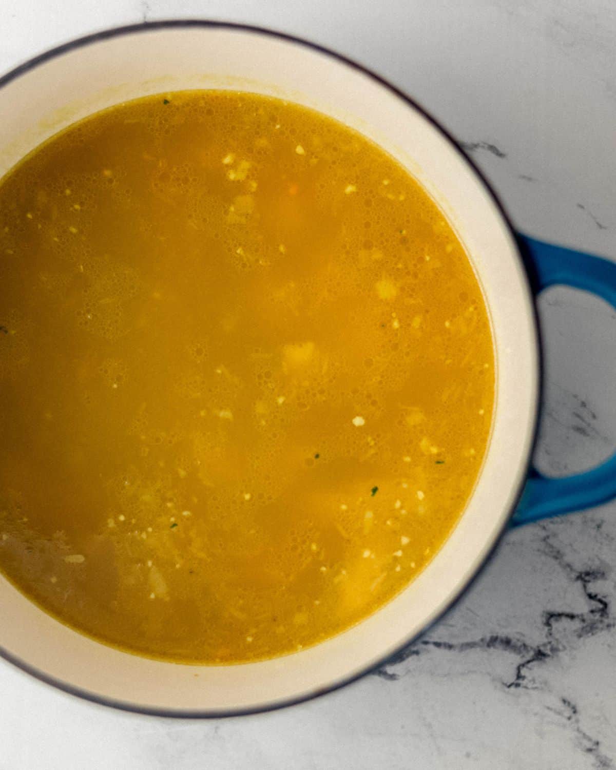 Overhead view of broth added to the stock pot with the other soup ingredients. 