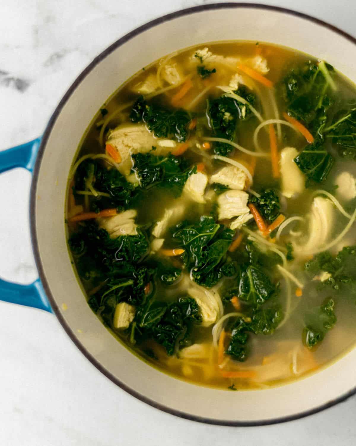 Overhead view of soup in stock pot on marble surface. 