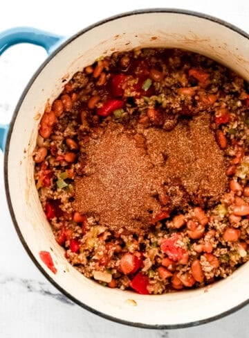 Overhead view of seasoning blend added to other ingredients in dutch oven.
