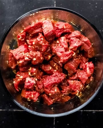 Steak and marinade in large glass mixing bowl.