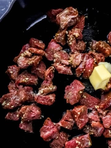 Steak added to cast iron skillet with butter.