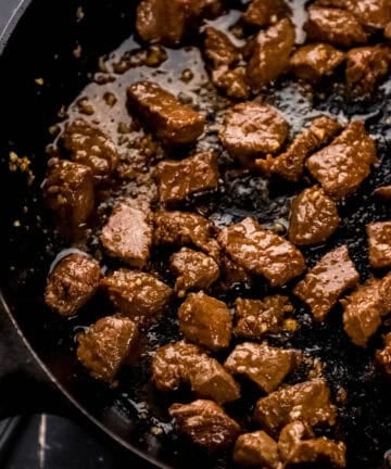 Steak cooking in cast iron skillet.