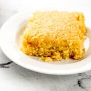 Close up front view of piece of cornbread on white plate.