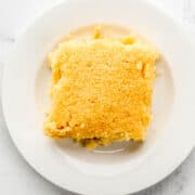 Overhead view of a single piece of cornbread on small white plate.