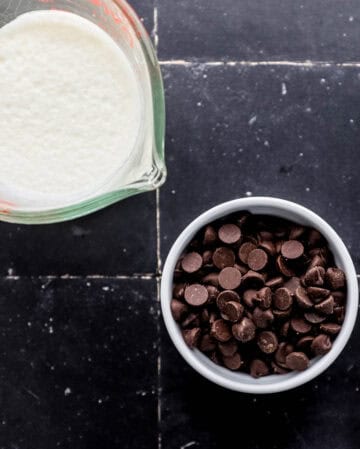 Small bowl of chocolate by a mixing bowl of cream.
