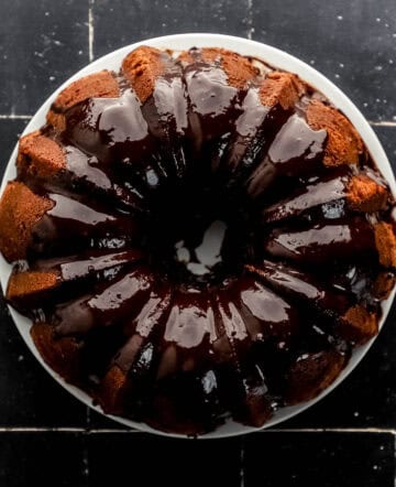 Overhead view of finished pound cake on white plate topped with ganache.