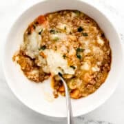 Overhead view of white bowl with single serving of shepherd's pie and spoon in it.