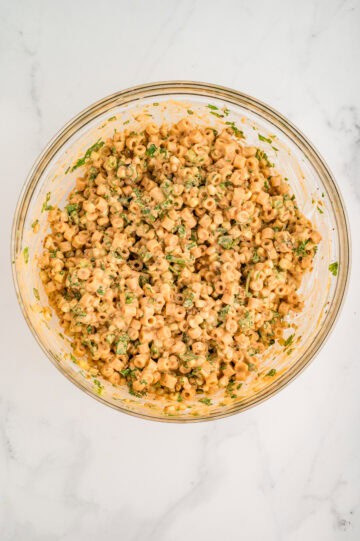 Overhead view of finished pasta salad in glass mixing bowl.