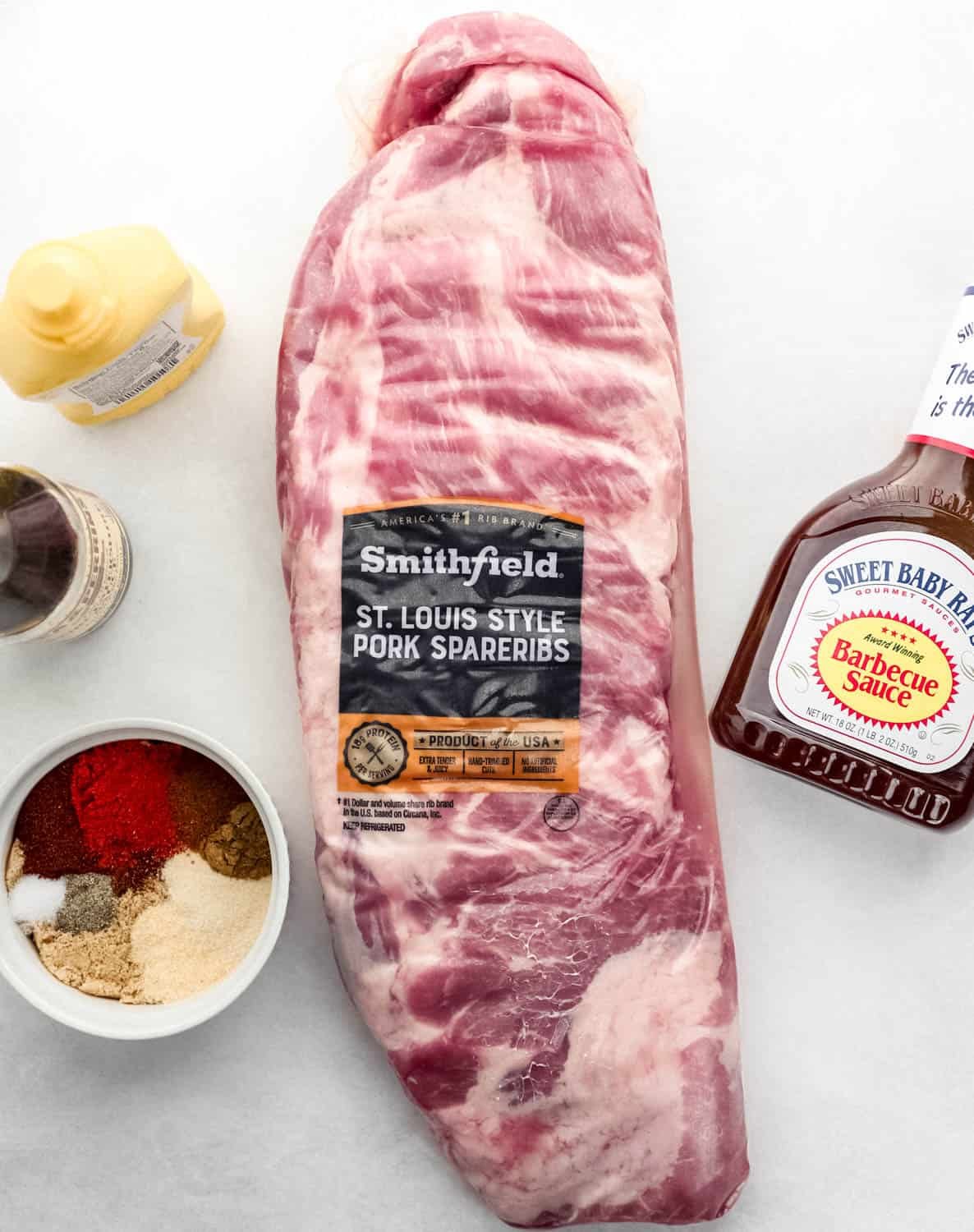 Overhead view of ingredients needed to make ribs on white surface. 