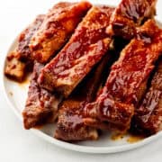Close up front view of finished ribs stacked on white plate.