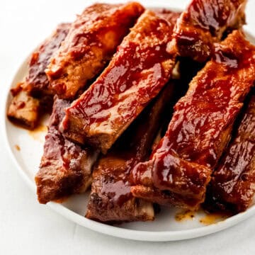 Close up front view of finished ribs stacked on white plate.