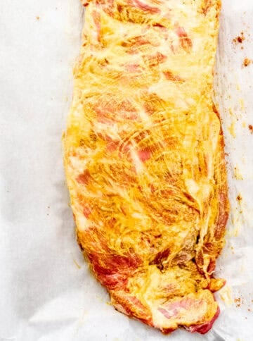 Ribs covered in mustard on parchment paper.