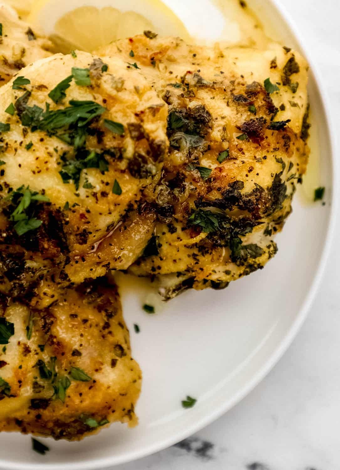 Close up view of finished chicken thighs on white plate. 