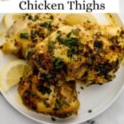 Overhead view of chicken thighs stacked on white plate on pin with text overlay.
