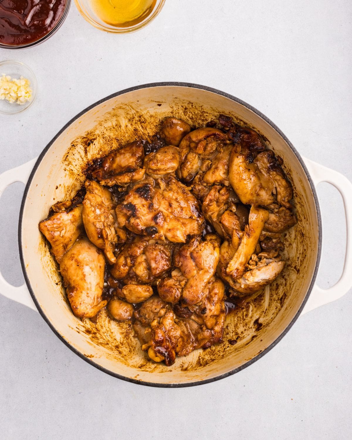 Overhead view of seared chicken in white dutch oven. 