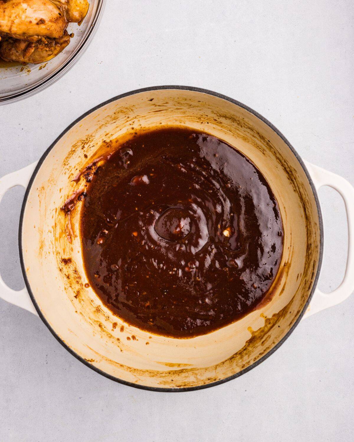Overhead view of barbecue sauce ingredients combined in white dutch oven. 