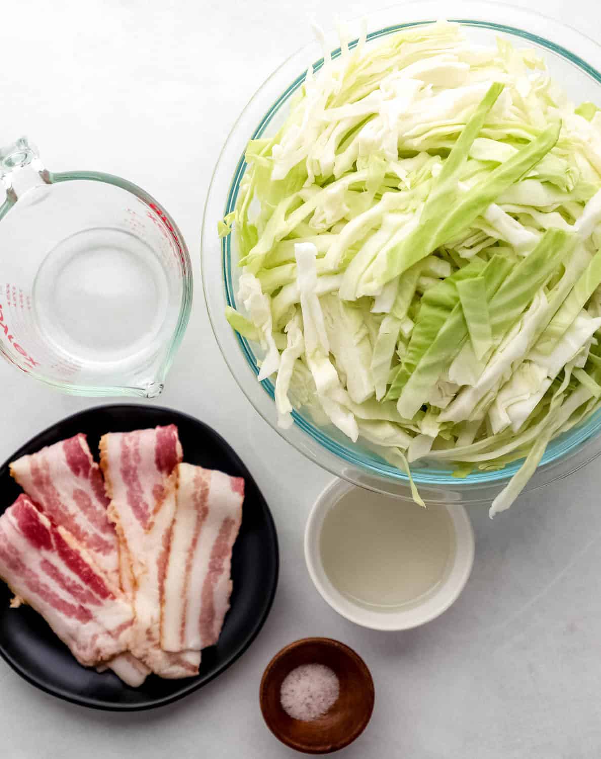 Overhead view of ingredients needed to make cabbage in separate bowls. 