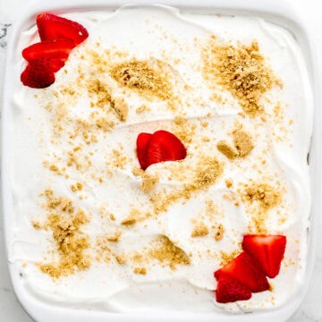 Overhead view of finished strawberry delight in white baking dish on marble surface.